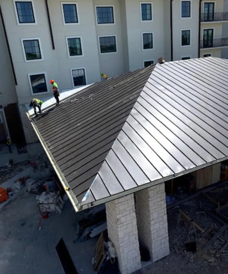 Crew installing standing seam metal roof panels on a commercial project in Elk River
